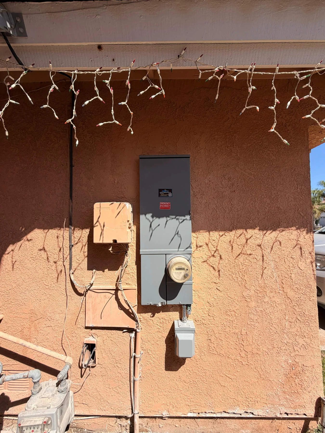 Exterior electrical panel and utility meter set into a peach stucco wall.